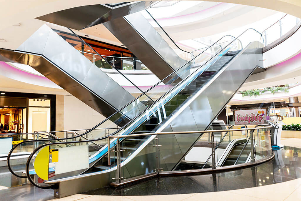 inside a shopping mall, with escalator and glass railings